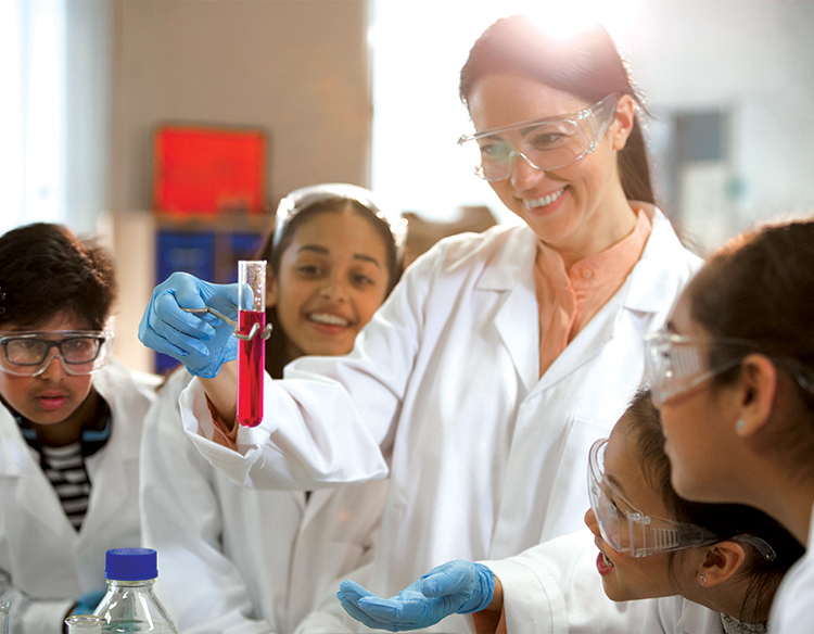 Chemistry teacher performing experiment in front of class of young students. 