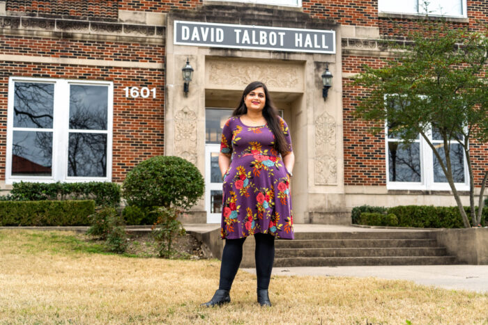 A female professor in front of a bricked building.