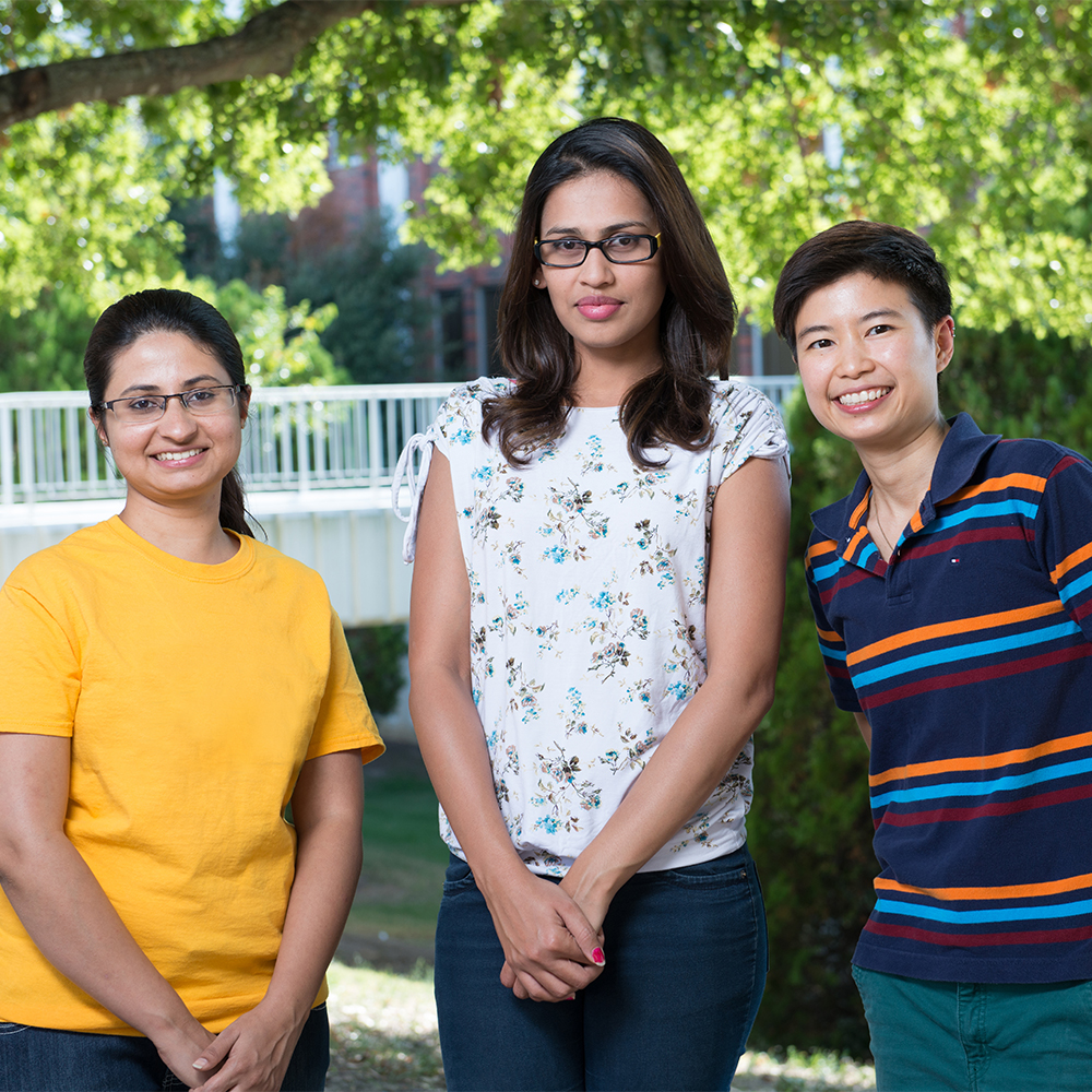 Three students smiling at the camera.