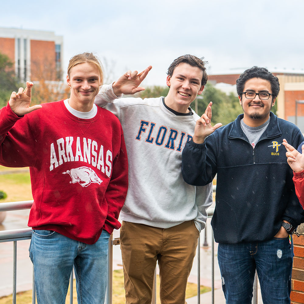 Three students wearing pullovers from other universities.