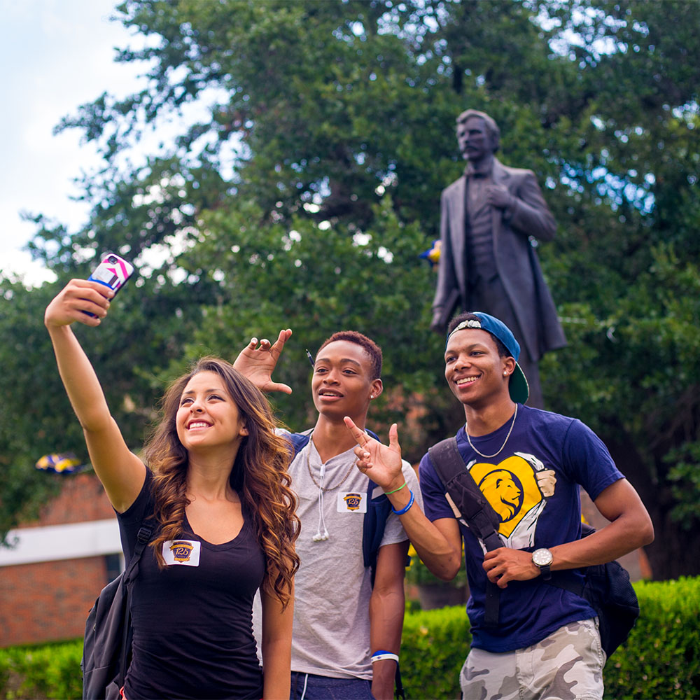 Three students taking a selfie wearing A&M-Commerce shirts.