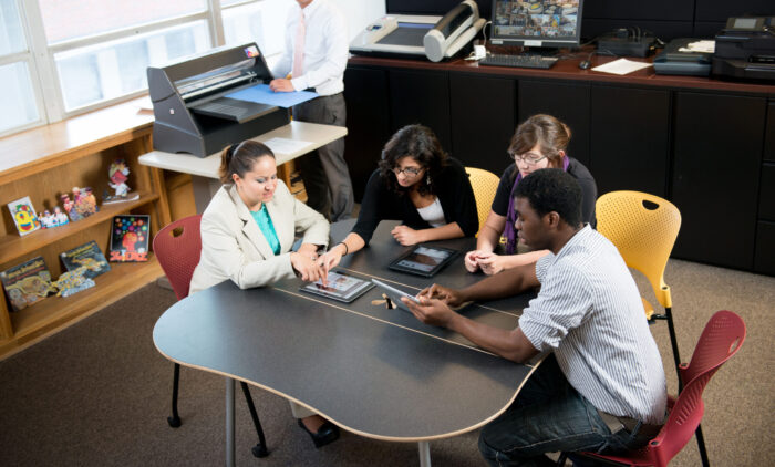 A group of student sitting at a table working on a project.