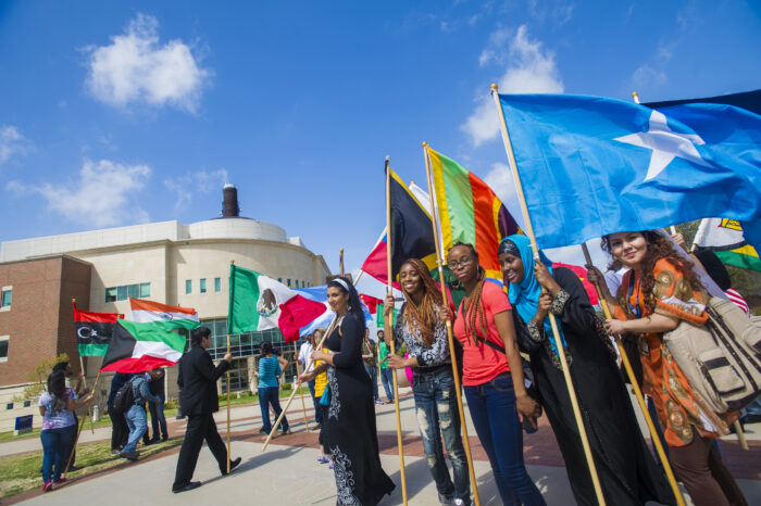 Students holding many national flags at a multicultural fest.