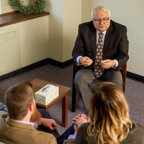 A heterosexual couple speaking with a male therapist.