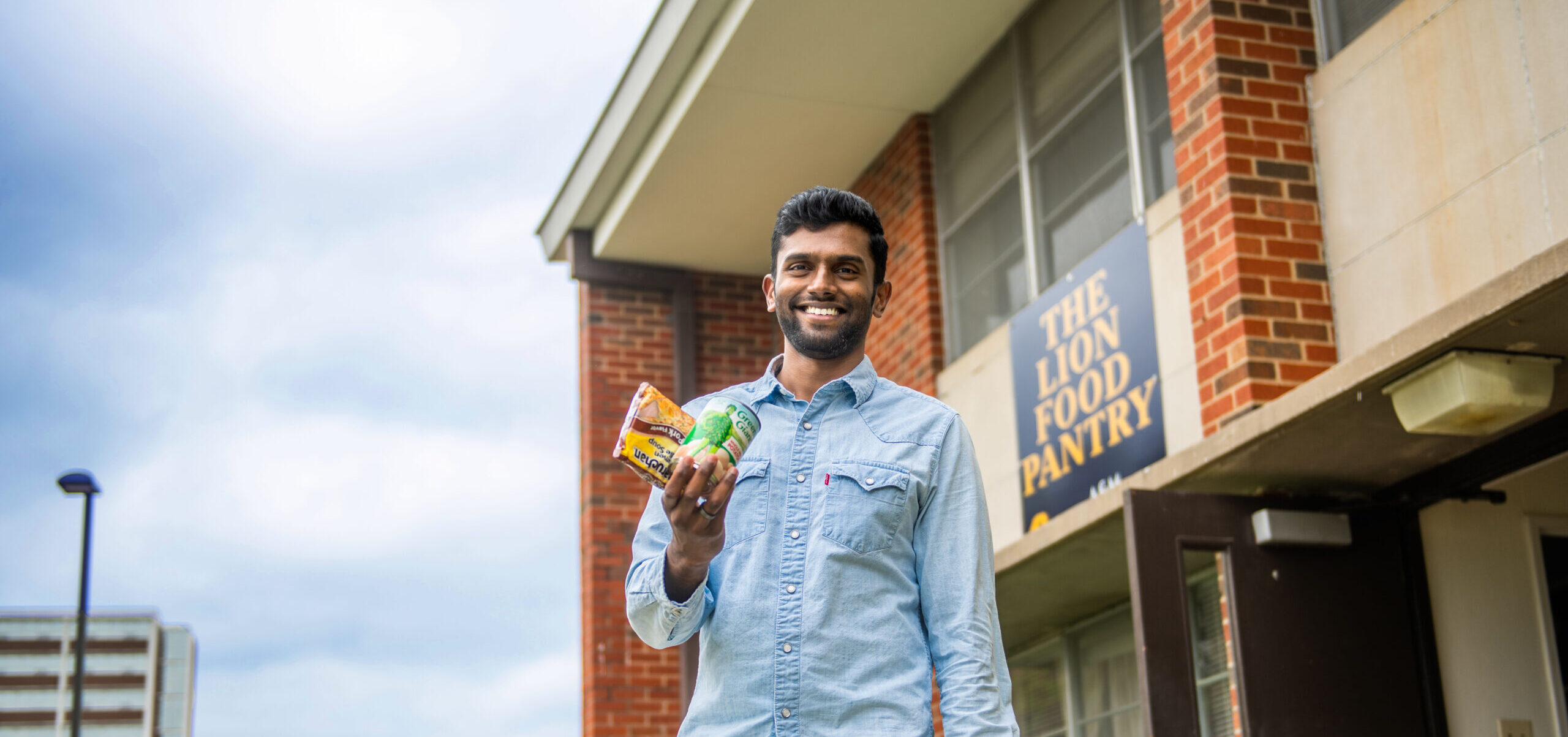 Male student holding on to food in front of the Lion Food Pantry.