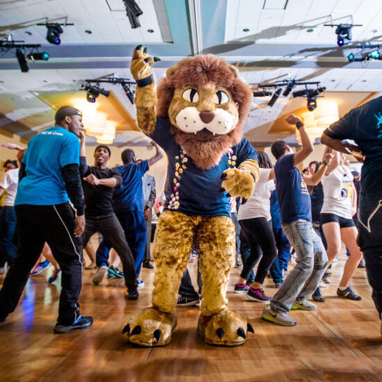 Lion mascot on the dance floor surrounded by students dancing.