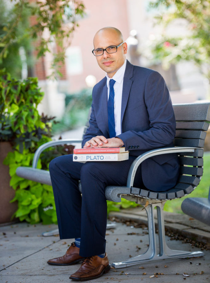 Dr. Mark Menaldo siting on a bench on campus.