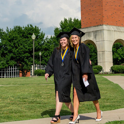 Two students on the Navarro College campus wearing cap and gown.