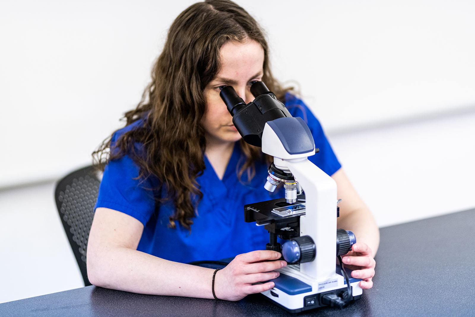 Student examine sample using a microscope.