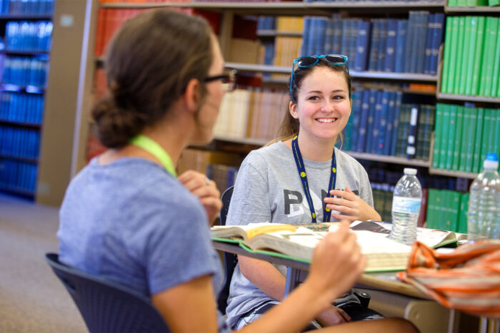 Two student happily studying in a library.