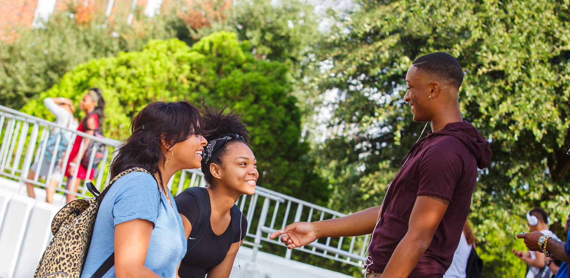 Two black female students smiling at a black male.