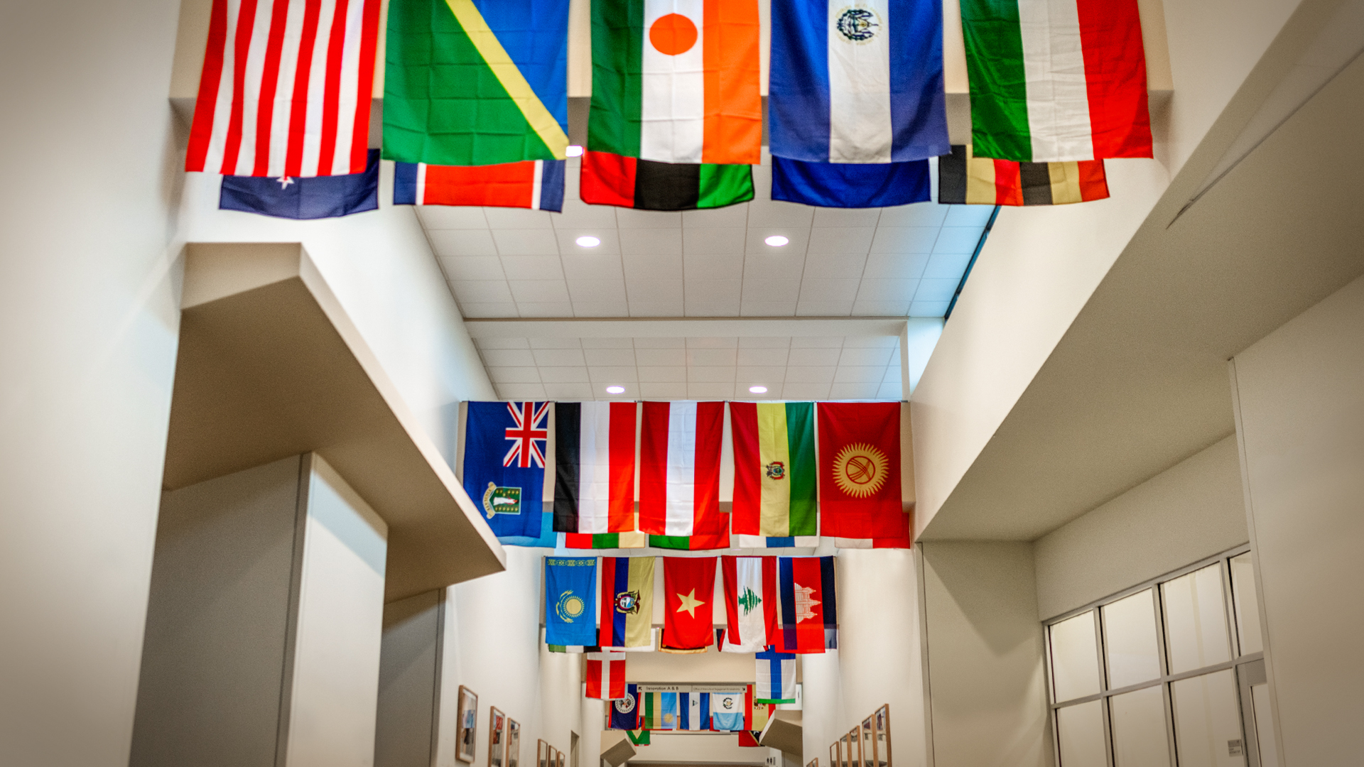 Inside of building with international flags on the ceiling.