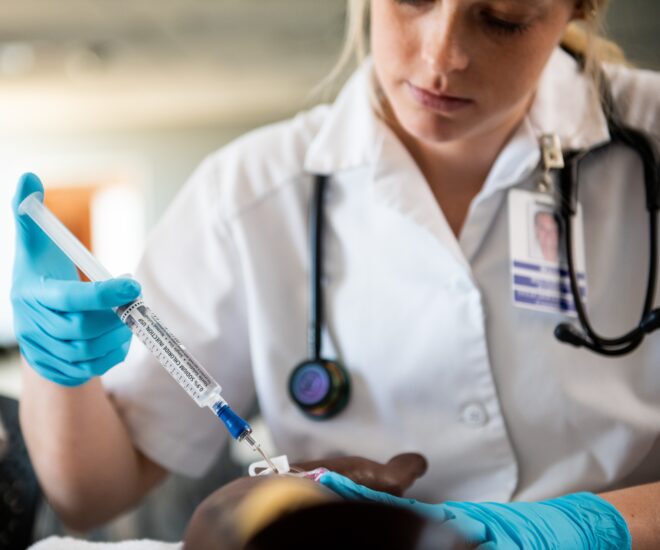 A Female student practicing to give an injection on a mannequin.