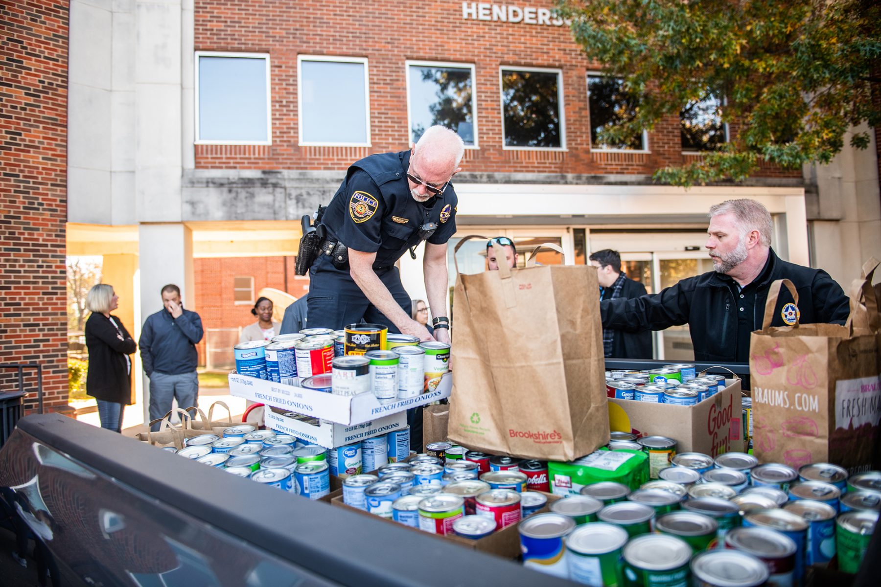 Officers helping load truck with food cans for donations.