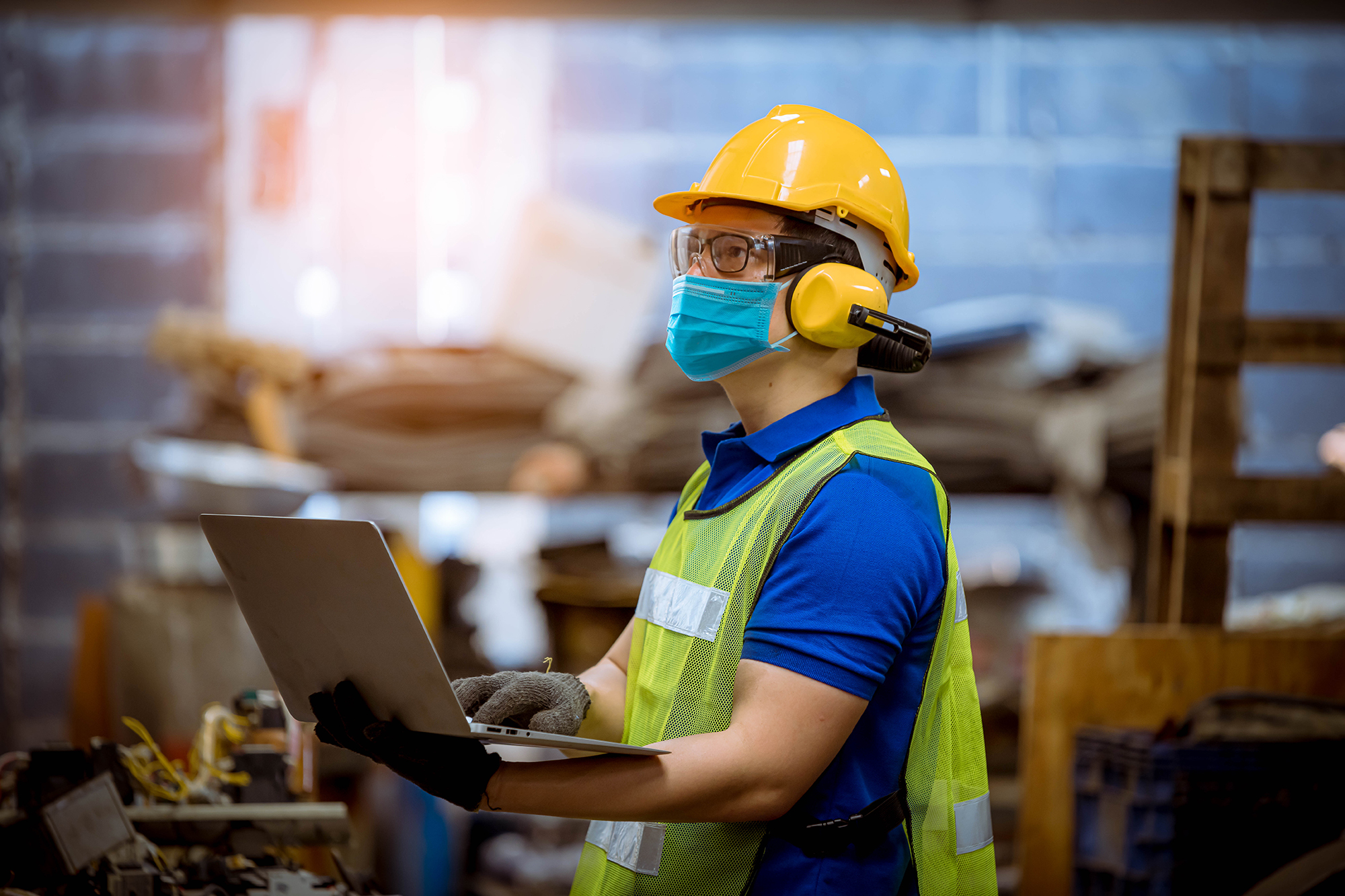 Engineer in personal protective equipment using a laptop on a construction site.