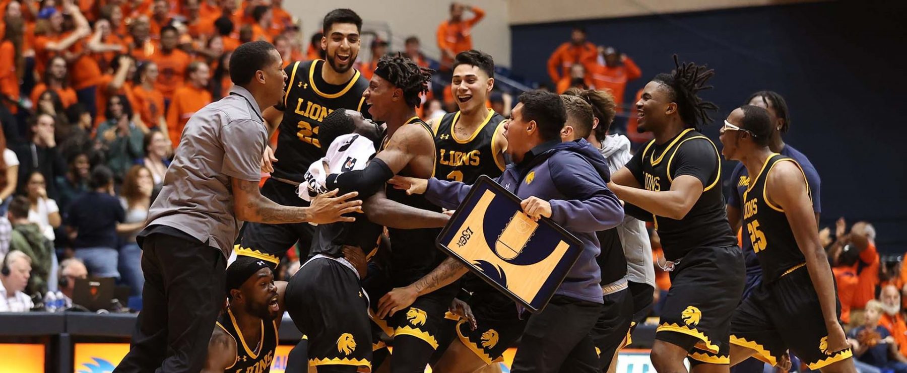 A group of male basketball players come together and celebrate.