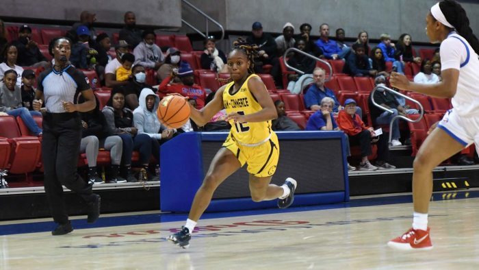 A female basketball player dribbling the ball.