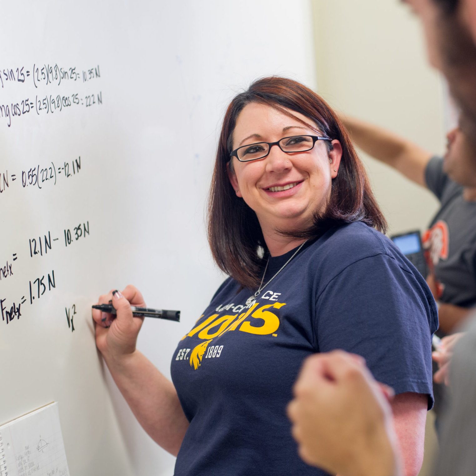 Woman solving a problem on a board.