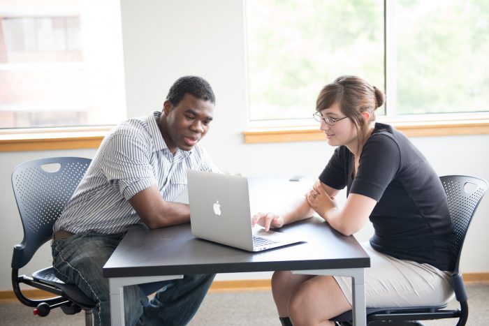 A female student showing a male student something on the computer.