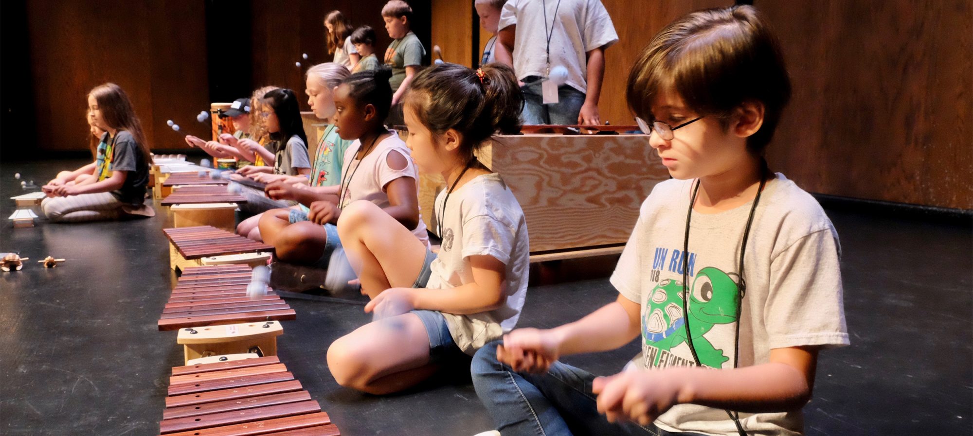 Young students playing instruments while following instructions.