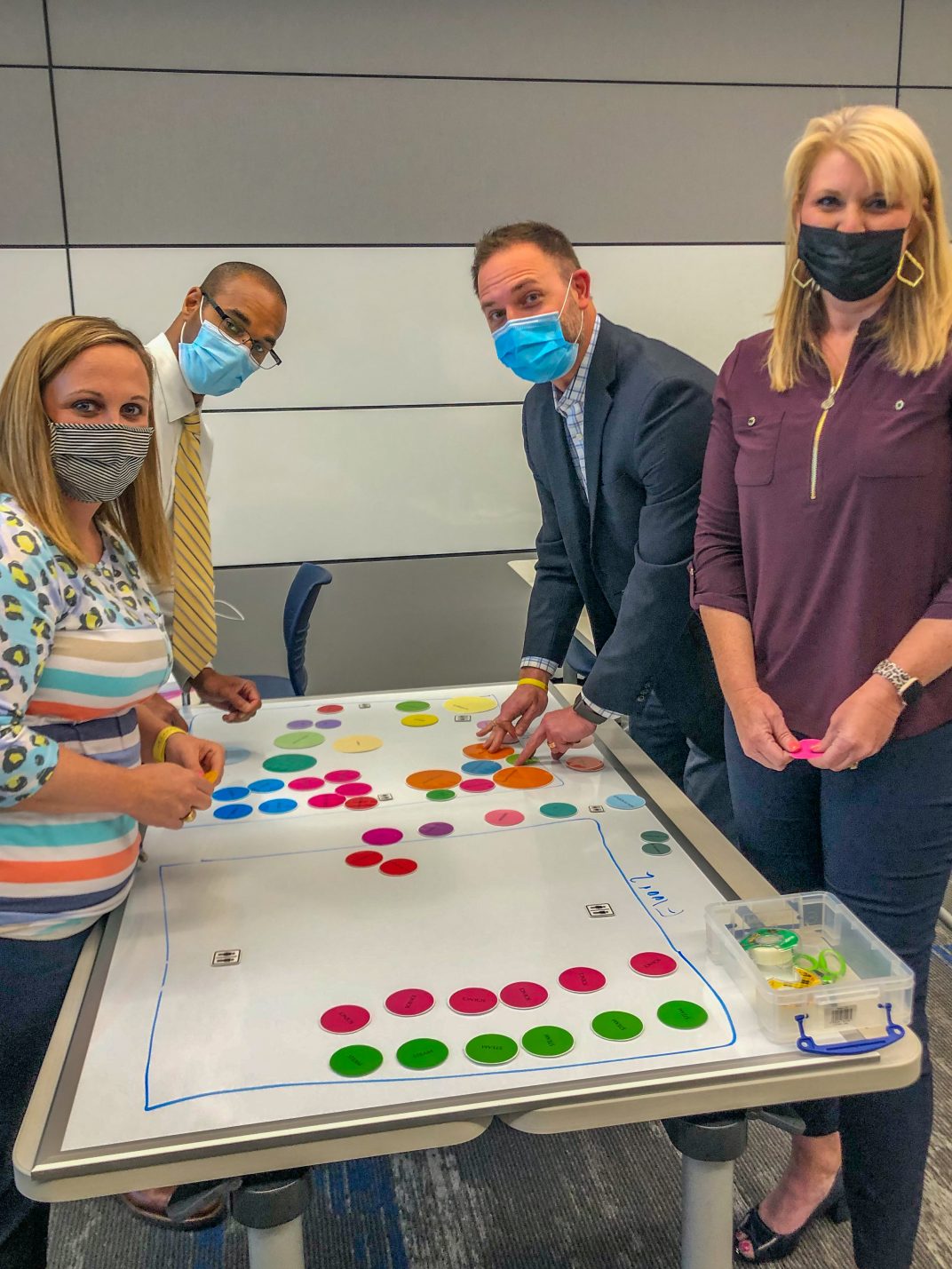 Students doing an exercise on a table with differently colored circles organized on a table.