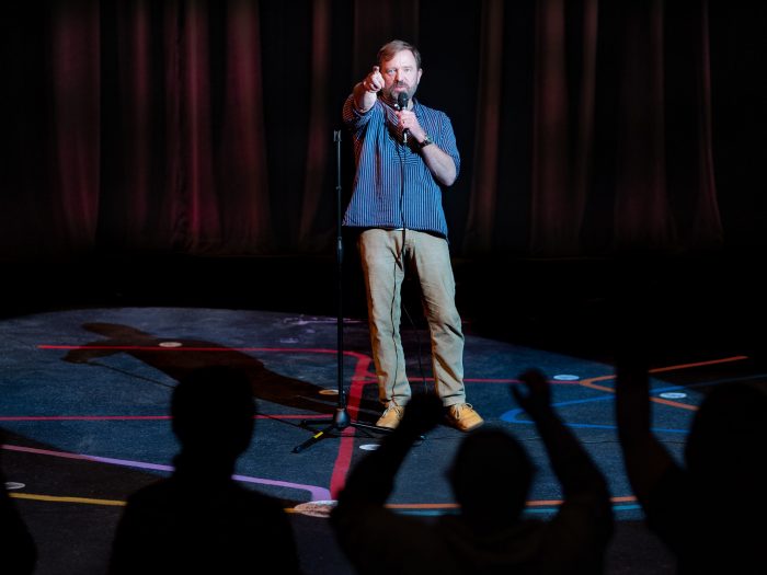 A professor stands on stage pointing back at the audience