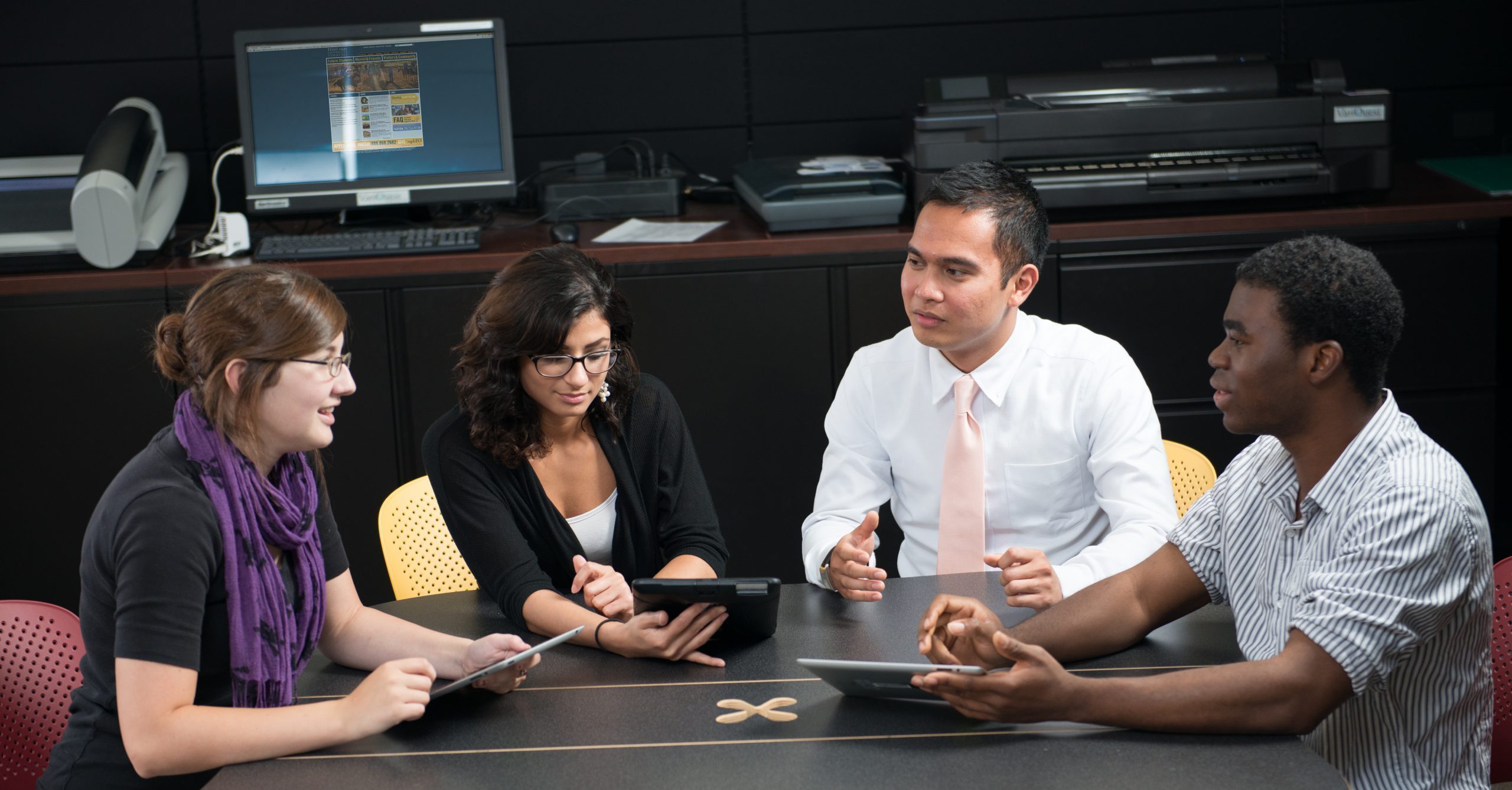 Executives at a conference table with smart devices