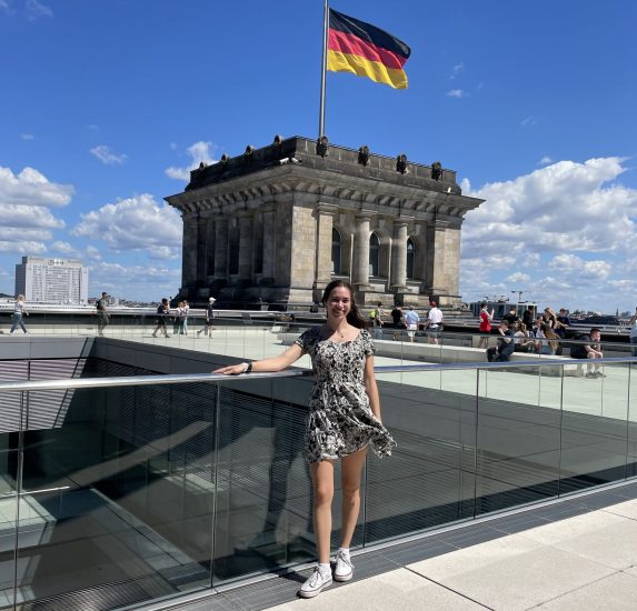 A young female in front of a building with the German flag.