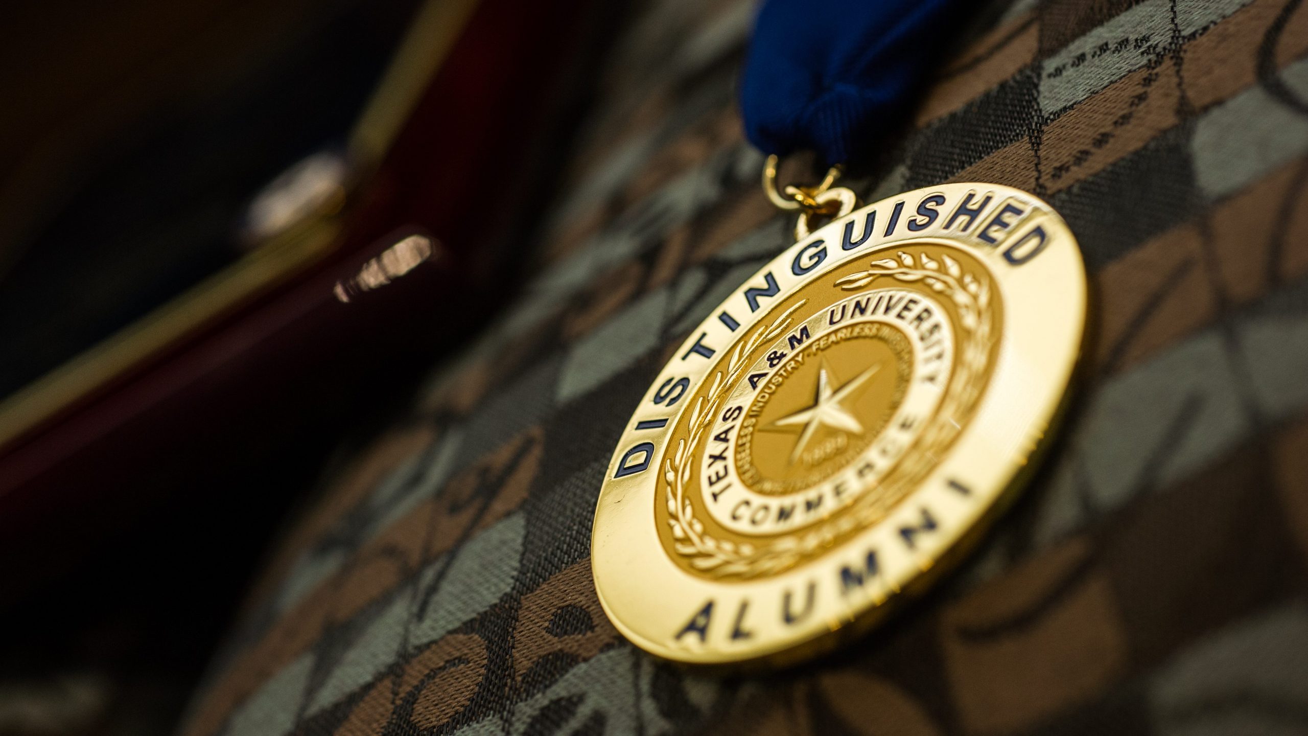 A golden badge with distinguished alumni.