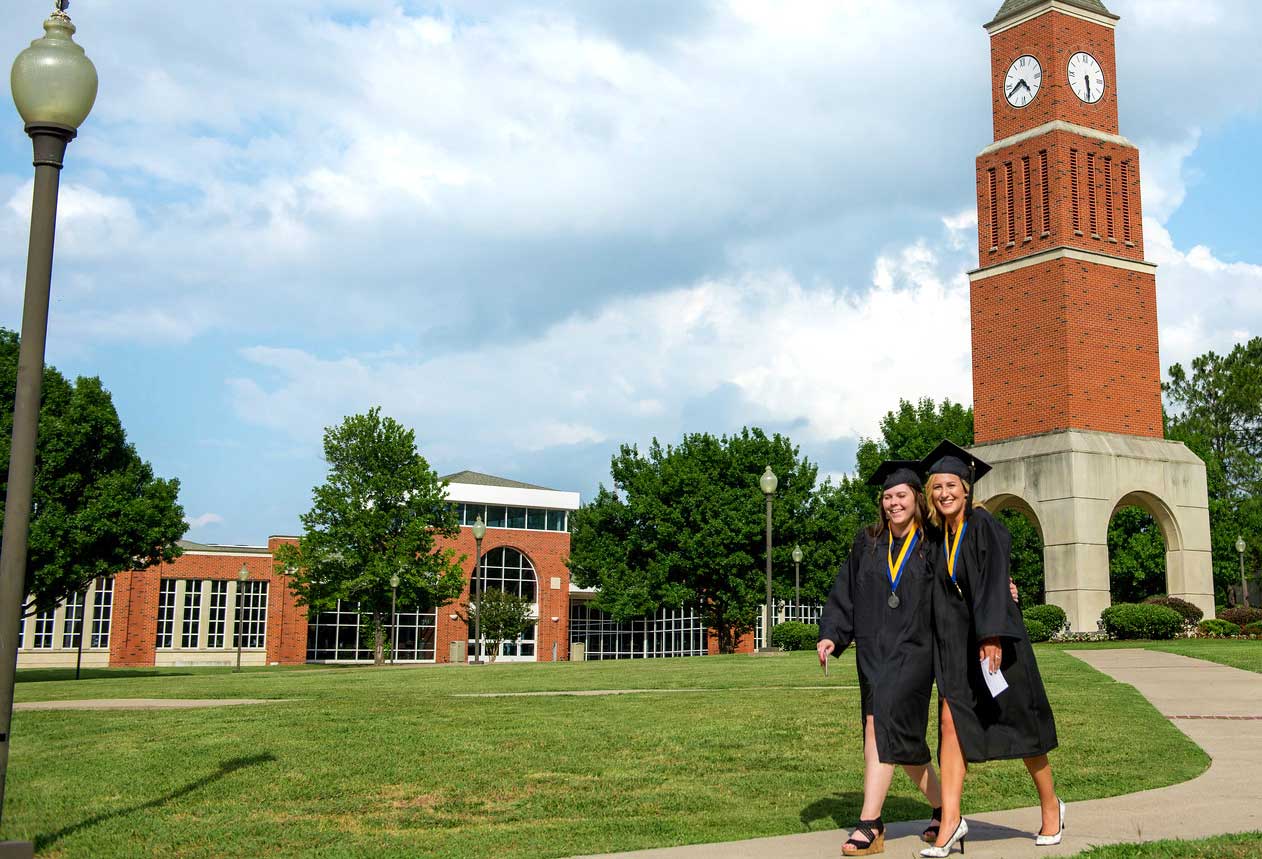 Two graduating females in front of the clock tower on the Navarro campus.