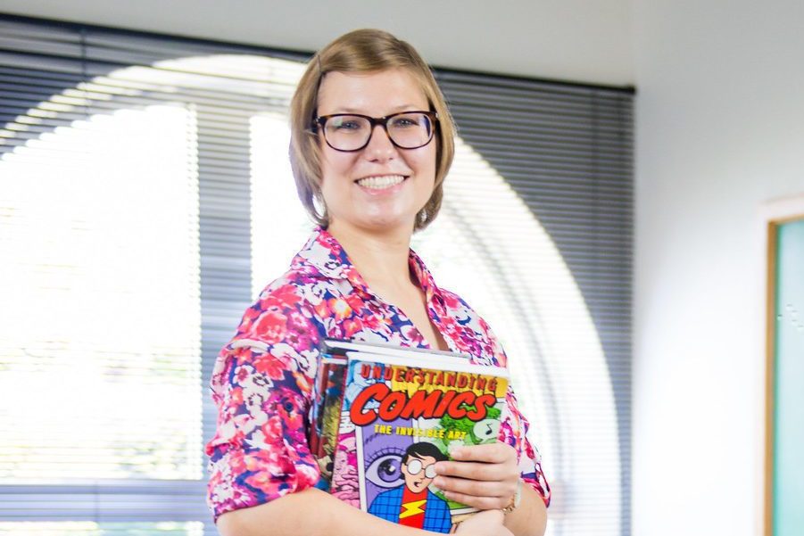 Woman standing in a classroom holding books.