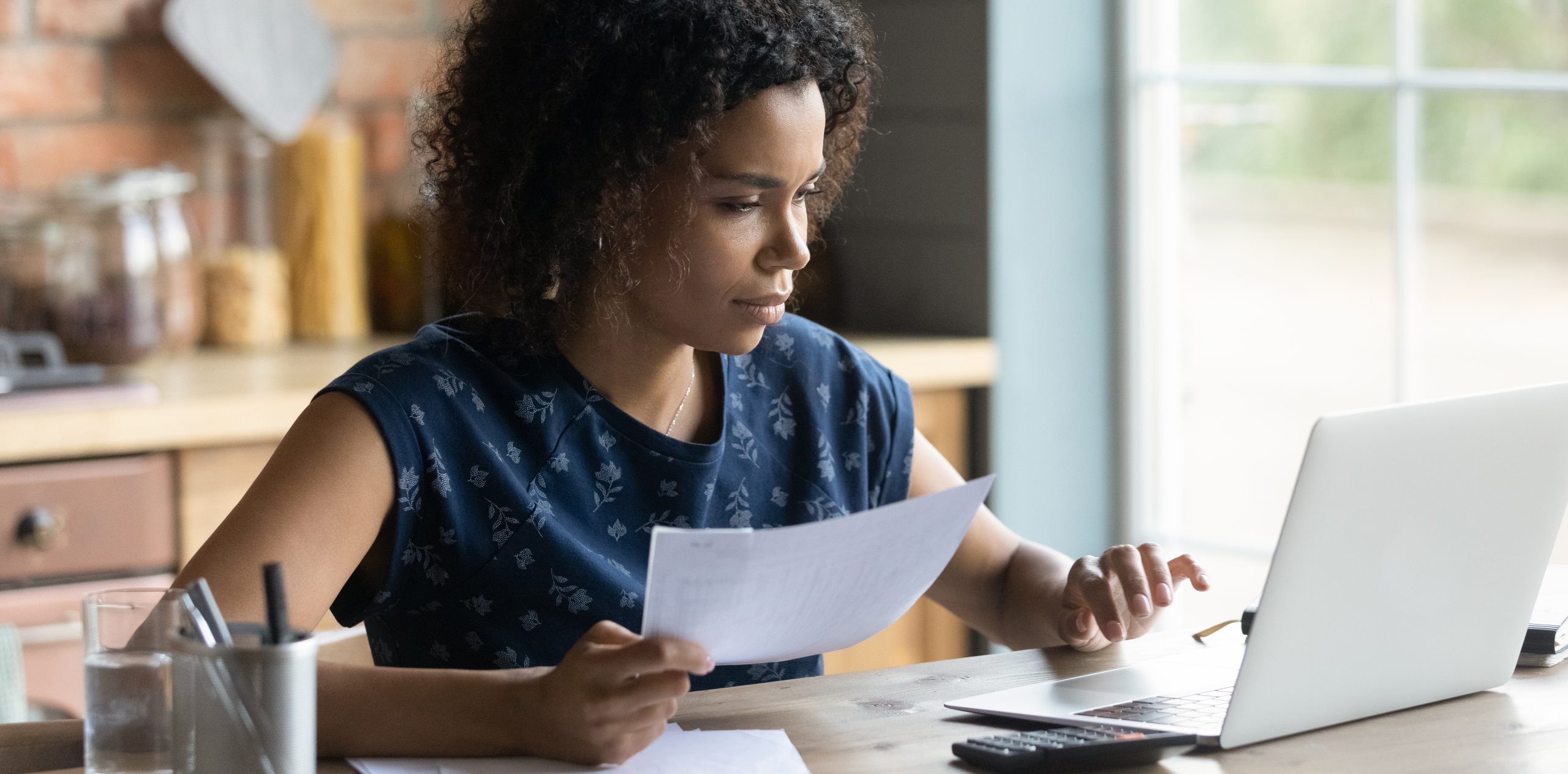 Serious millennial African American woman calculating taxes