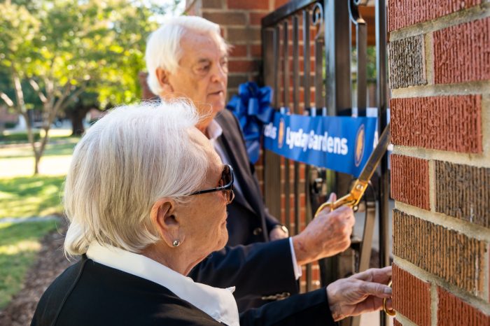 Two senior individual cutting the ribbon for the garden.