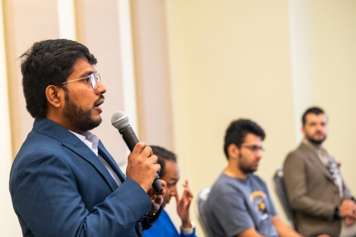 A male speaker, speaking to a group not seen in the photo.