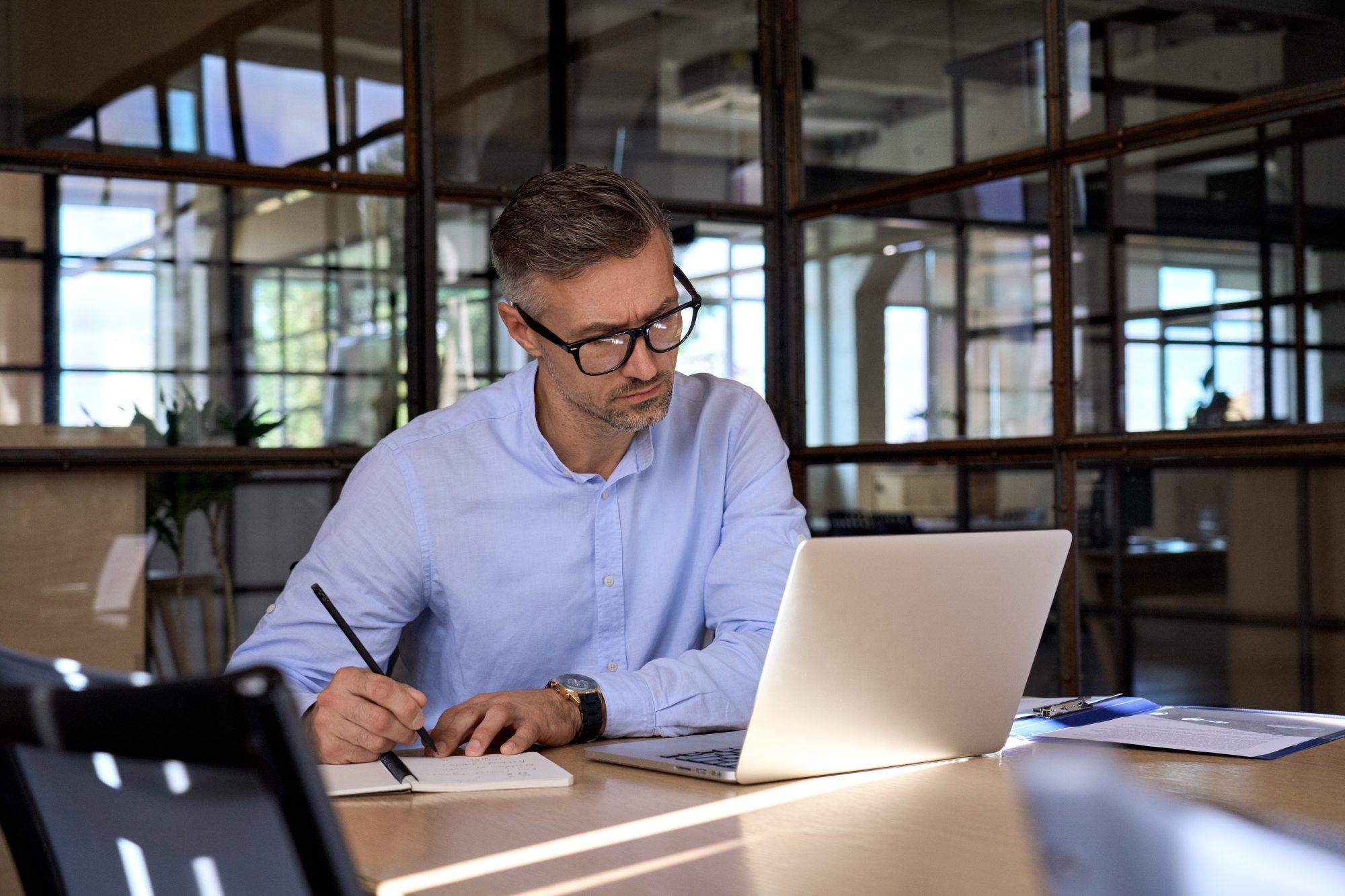 Mature business man manager looking at laptop watching online webinar in office.