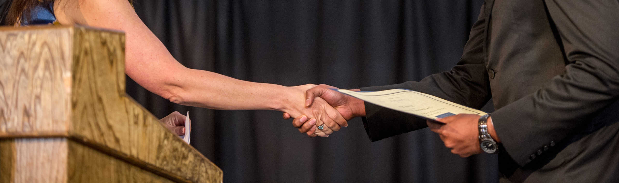 Two individual handshaking with an envelope.