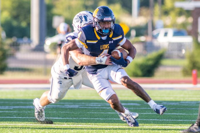 A male football player tackling another male football player.