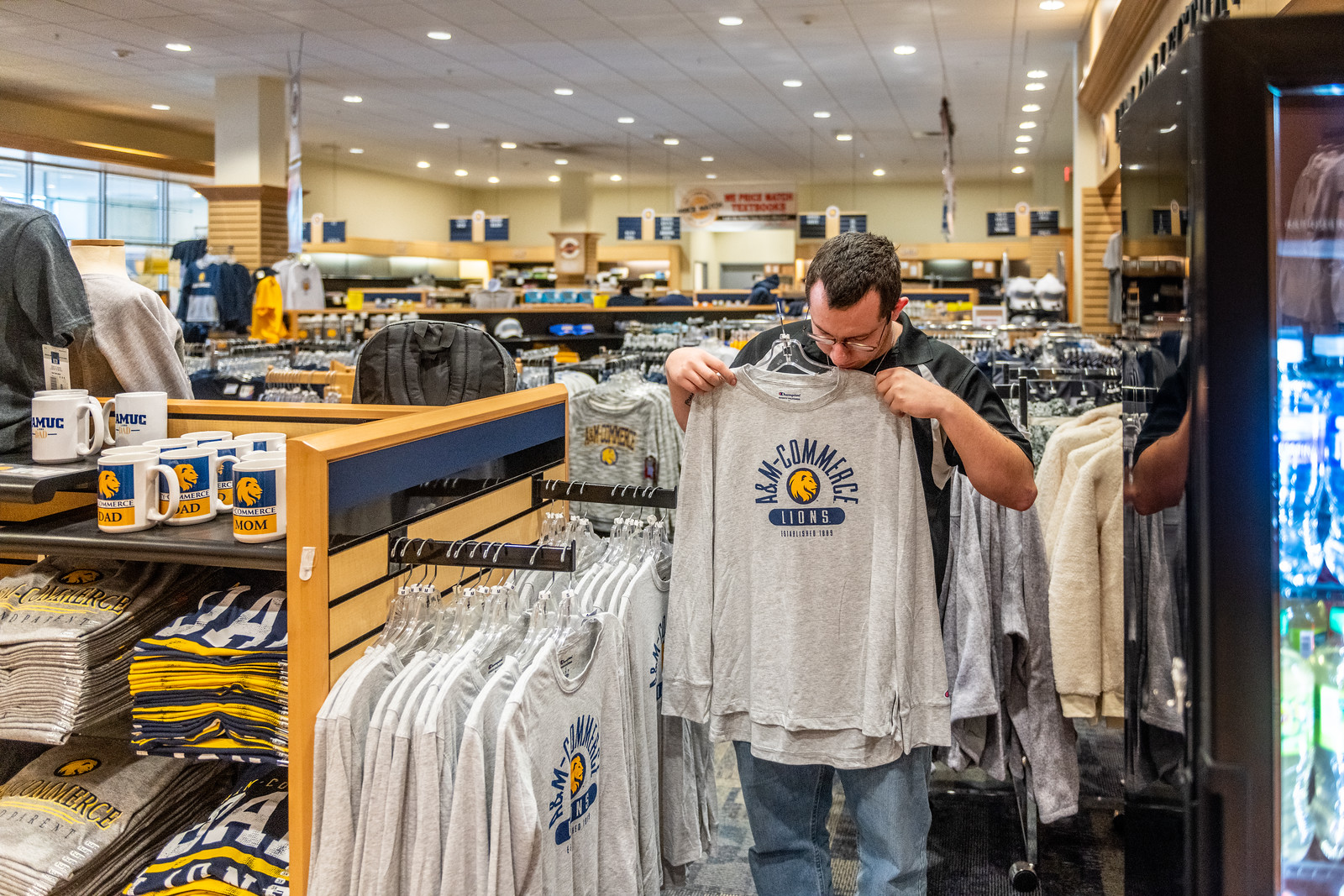 A male looking at a lions shirt at the bookstore.