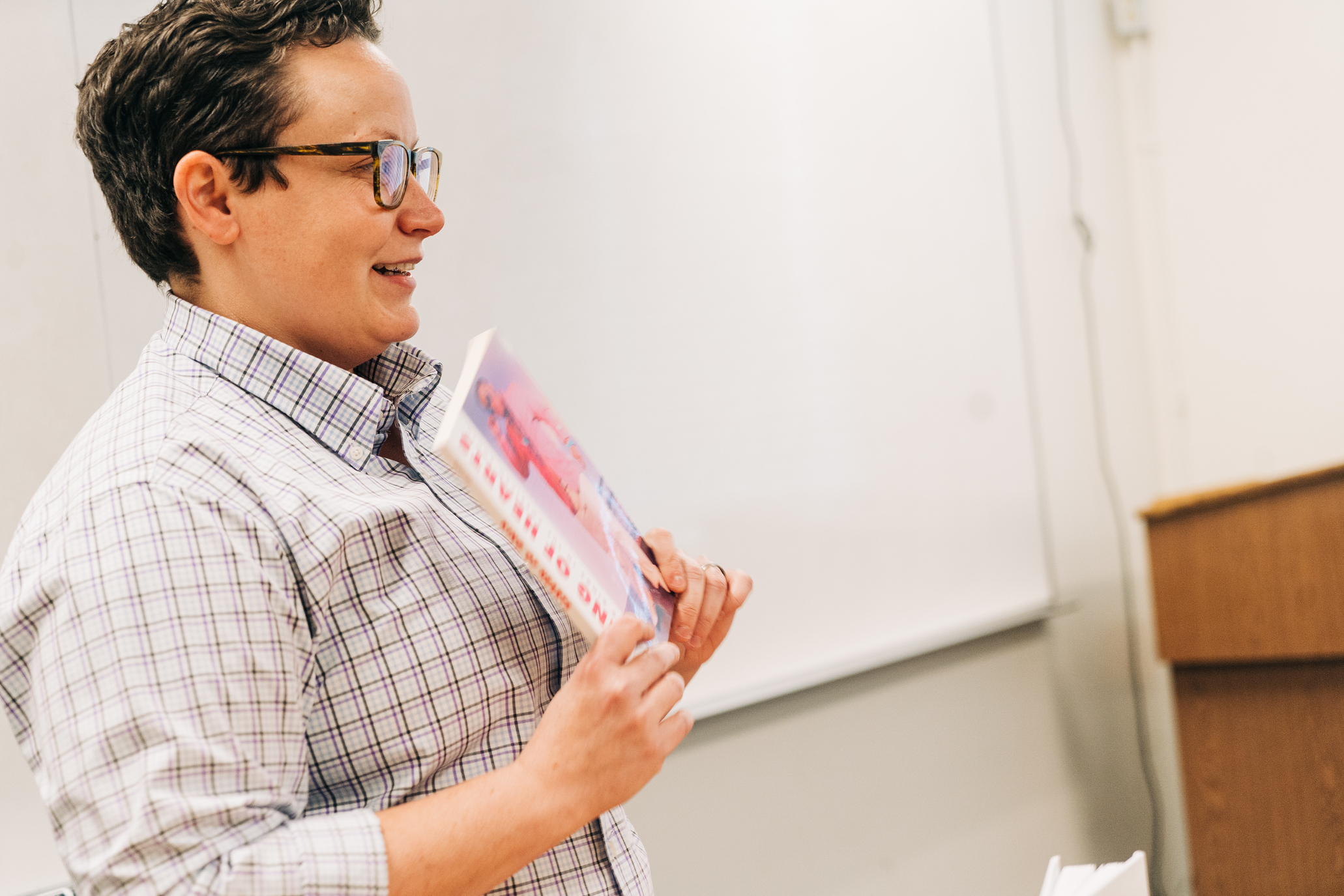 A professor holding a book showing it to the class.