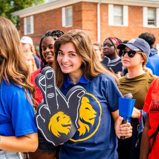 A Caucasian female smiling with the leo hang sign in front of her