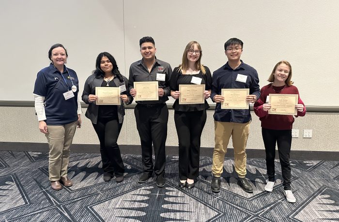 A professor and five students pose with certificates.