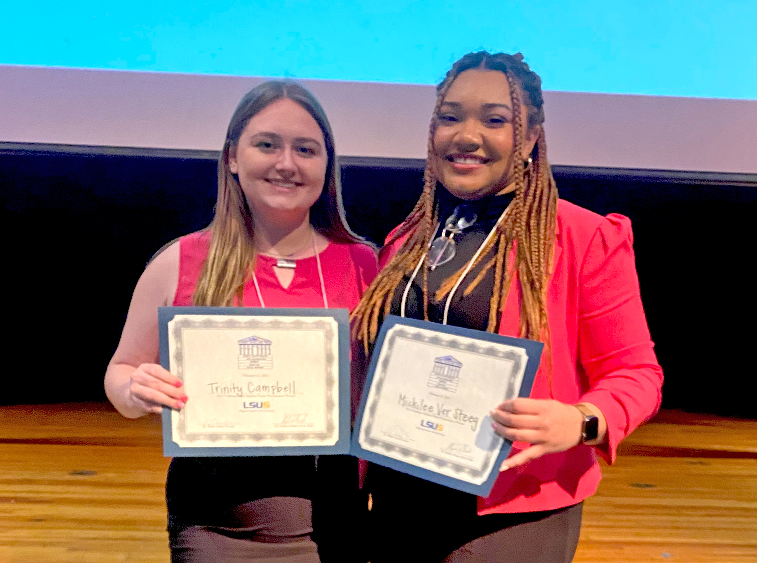 Two students pose side-by-side with their award certificates.