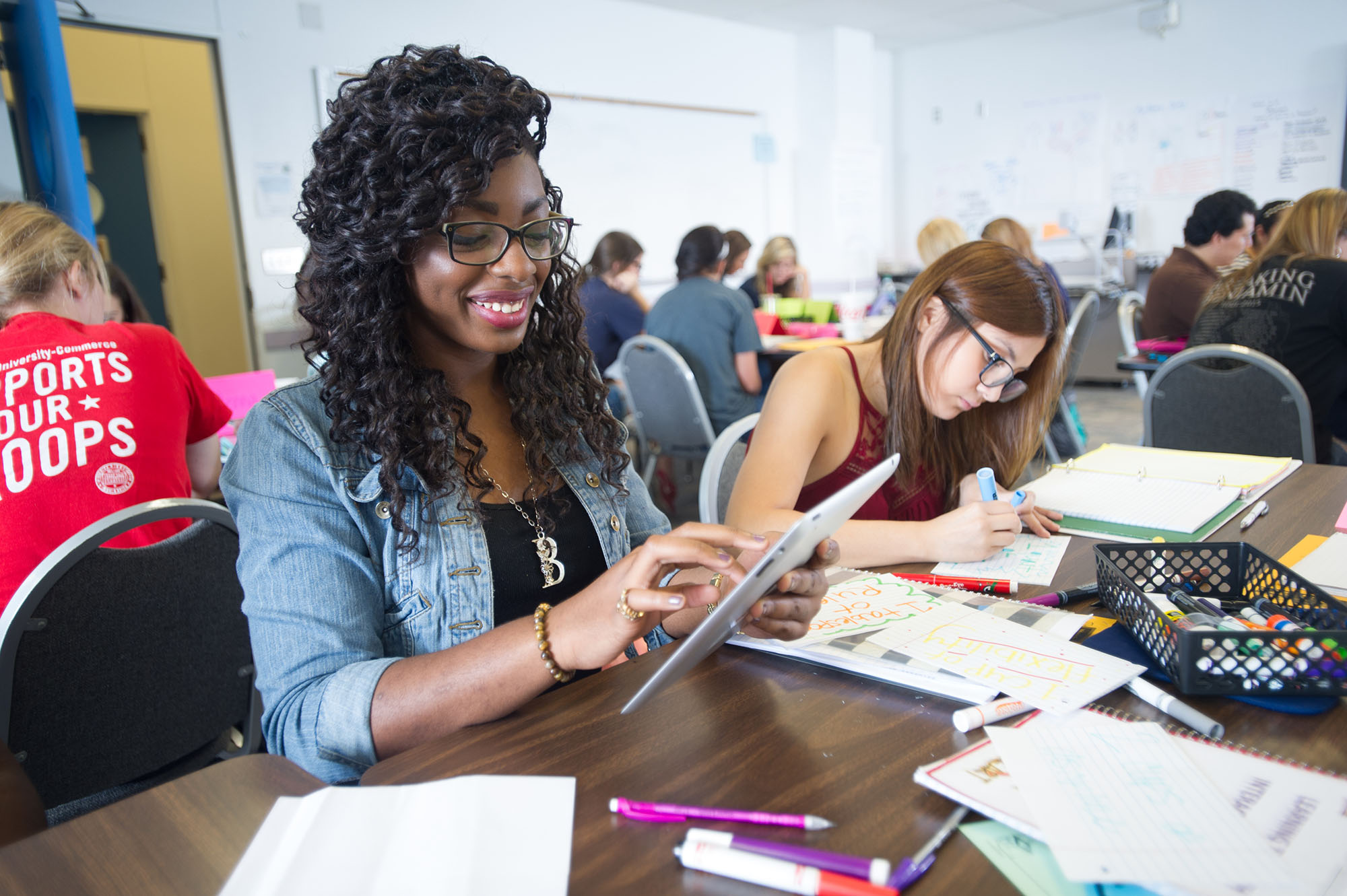 A female student using a tablet for an assignment she is completing with a colleague.