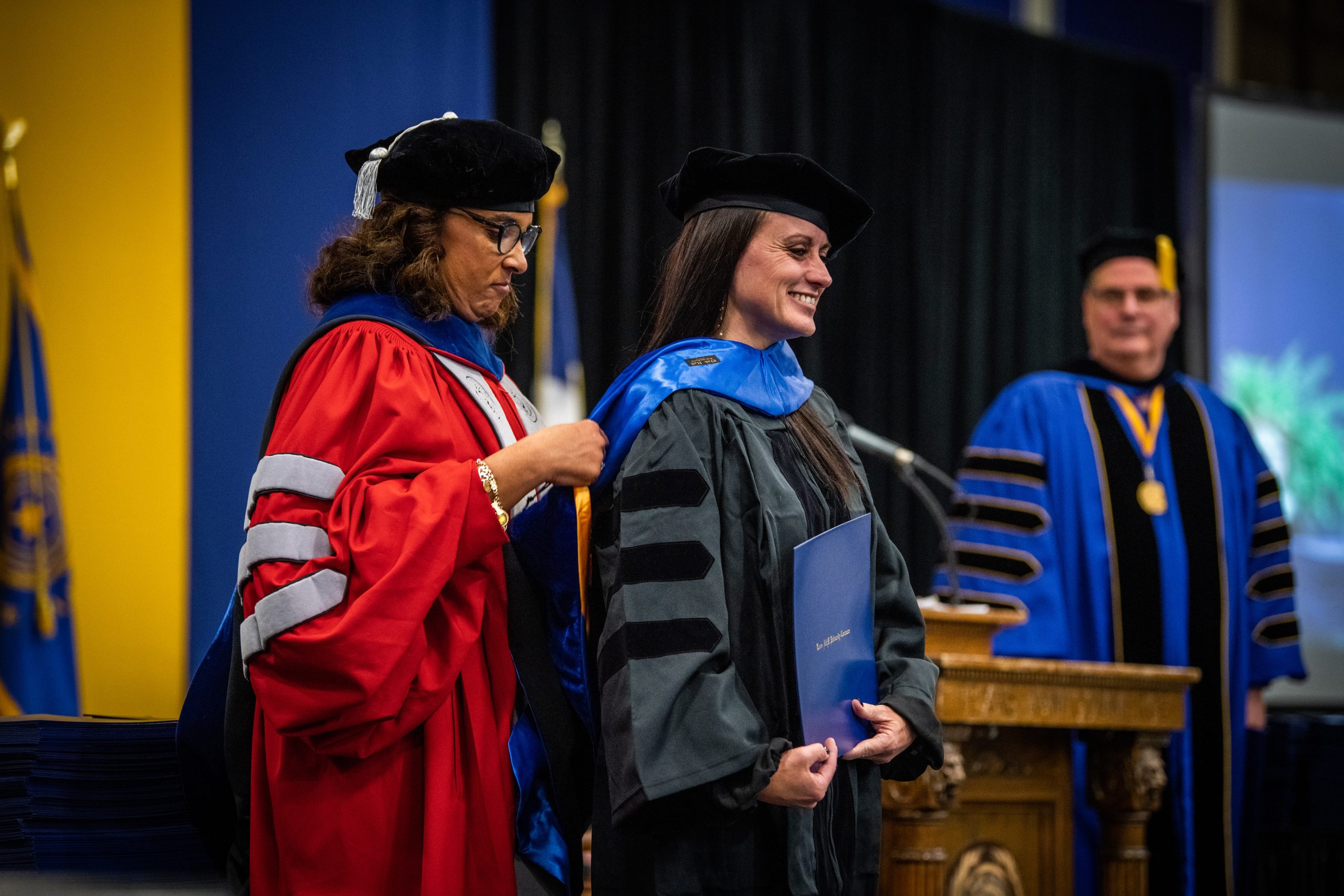Female professor hooding a female graduate student at graduation.