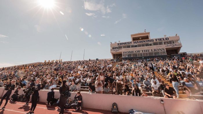 Football field and stands are framed by a blue sky.