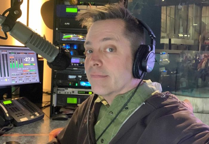 A male in a radio studio looking at the camera.