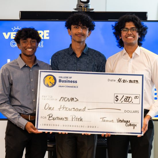 Three people hold an oversized novelty check for $1,000