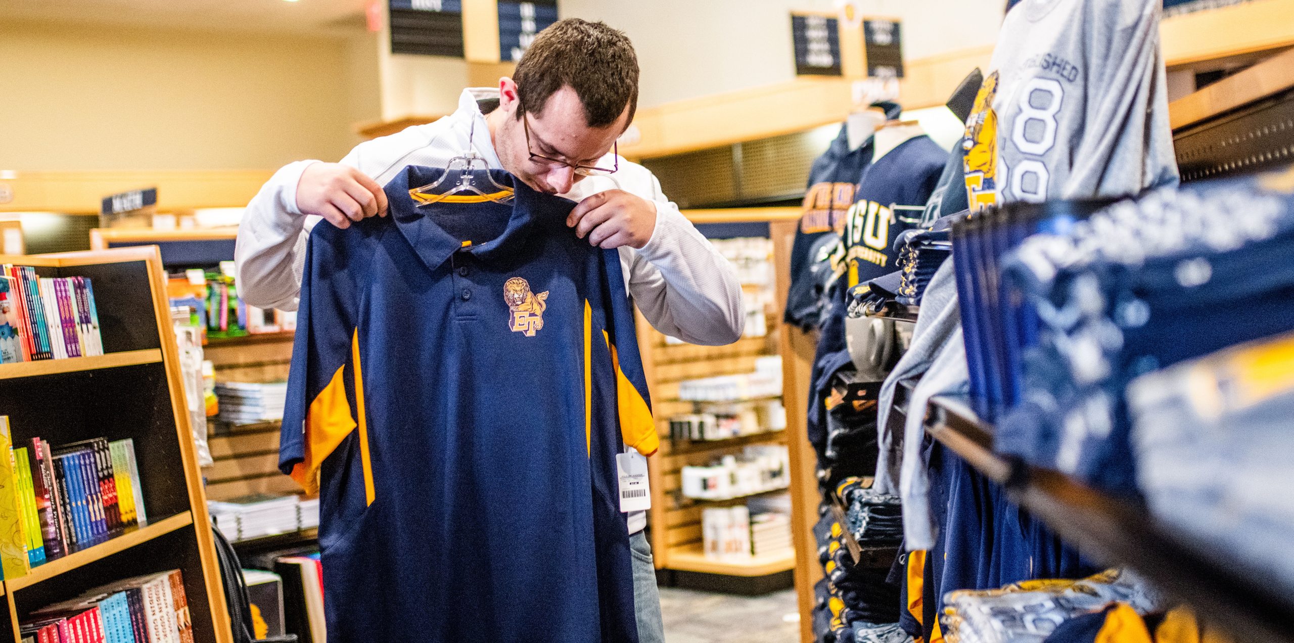 A male student looking at a A&M-Commerce t-shirt.