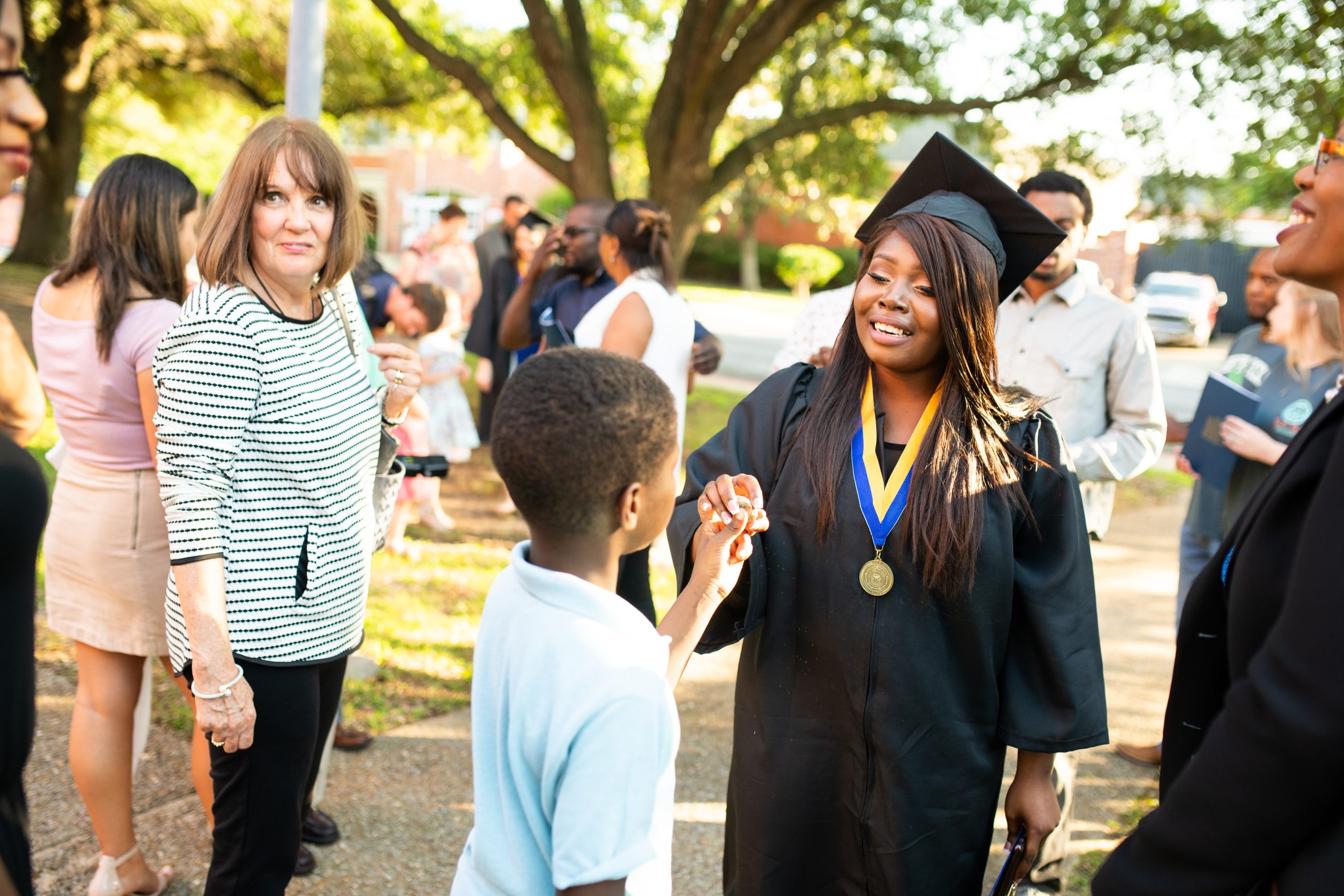 A graduating mother touching her son's hand.