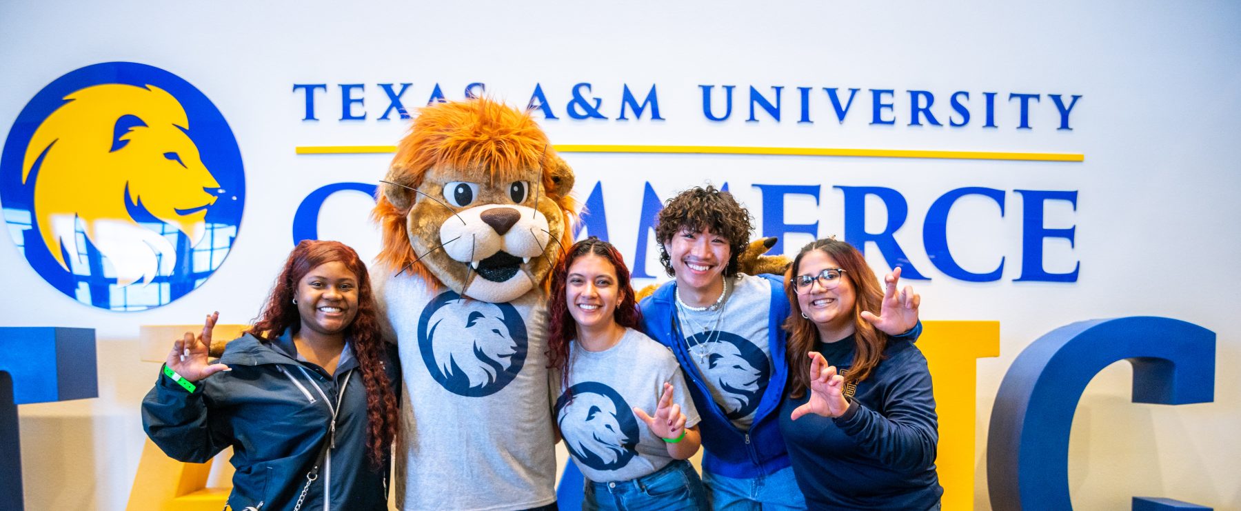 Four students pose with Lucky the Lion mascot.